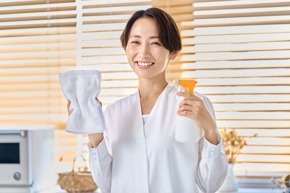 掃除道具を持つ笑顔の主婦