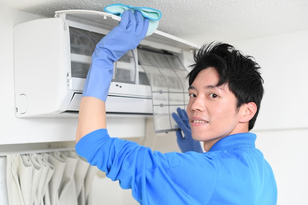エアコンのクリーニングをする作業服の若い男性