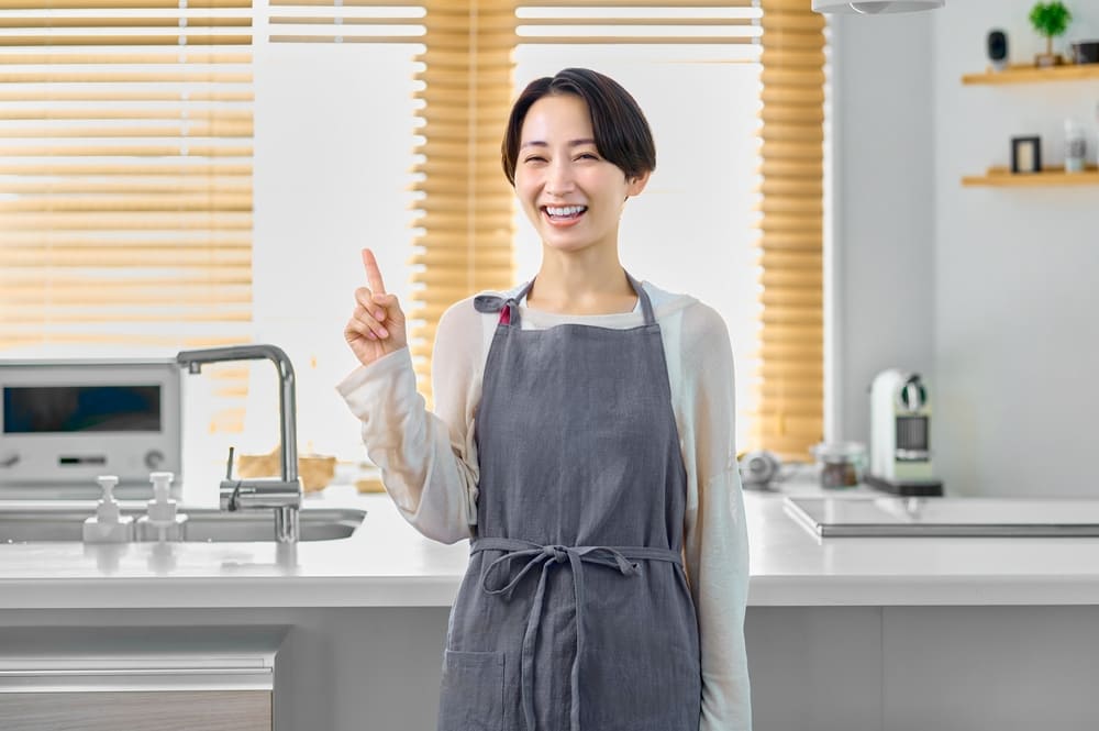 キッチンで指差しポーズをする主婦
